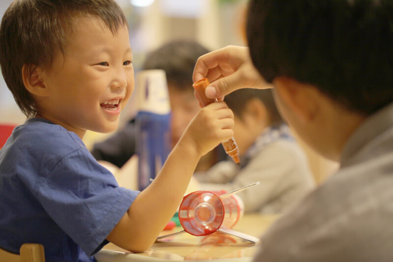 学生とペットボトルに色付けする園児