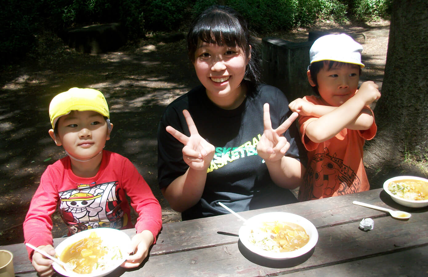 できあがったカレーを食べる学生と子どもたち