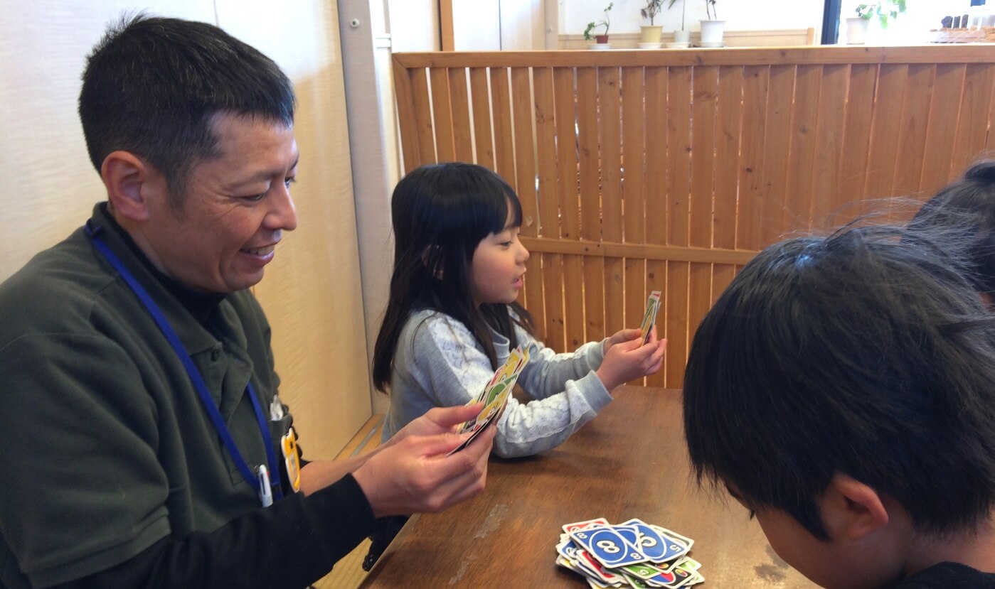 カードゲームをする職員と子ども