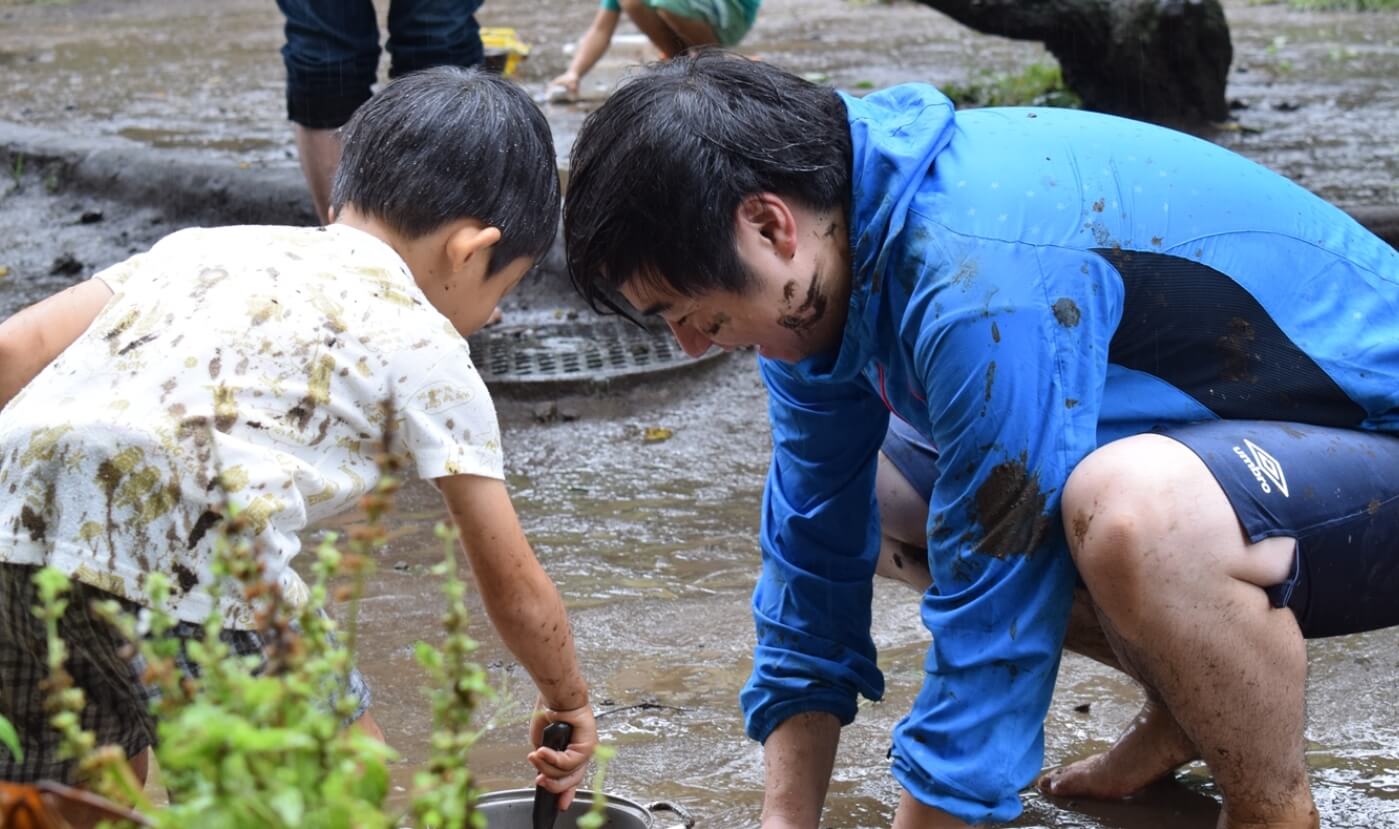 泥んこ遊びに夢中になる子どもと先生