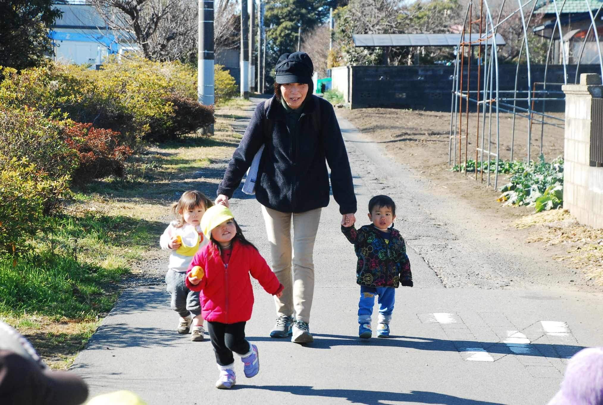 先生と手を繋いで散歩する園児