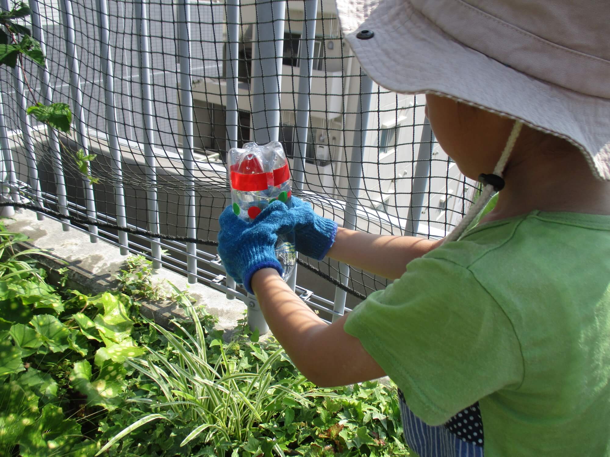 ペットボトルじょうろで水やりする子供