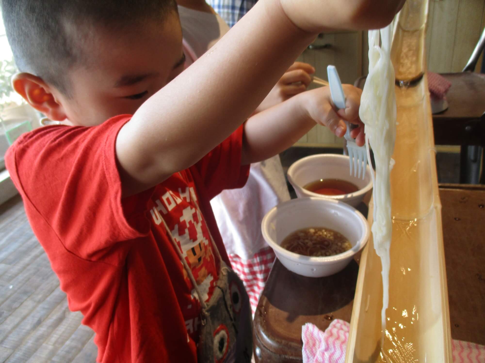 流れるそうめんをすくう子ども