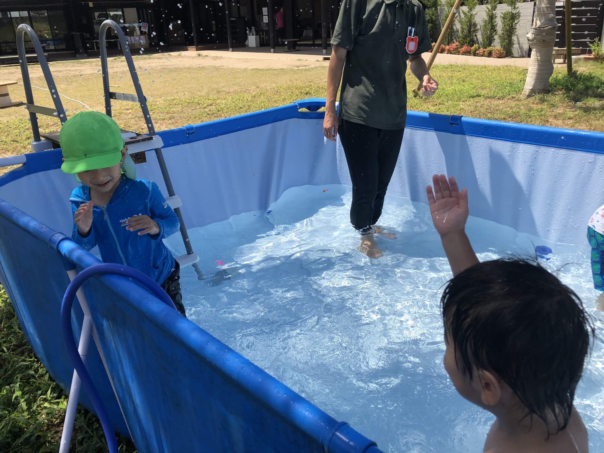 プールで水のかけあいをする子どもたち