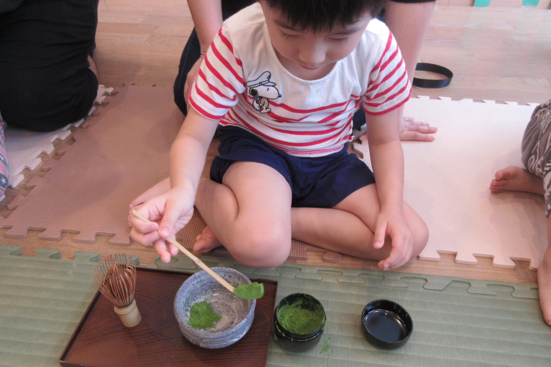 さじで抹茶の粉を入れる子供