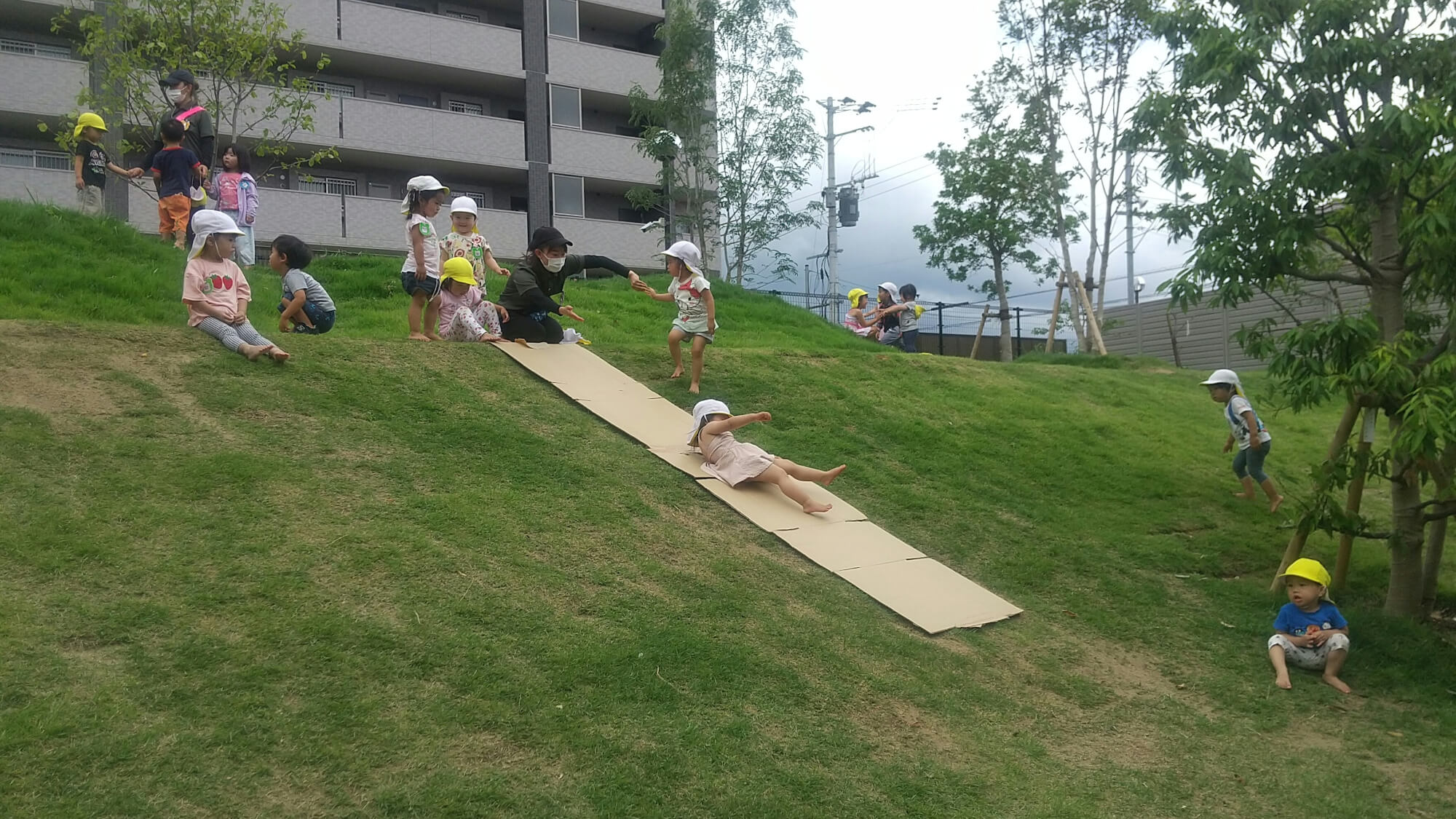 築山を滑り台にして遊ぶ子どもたち