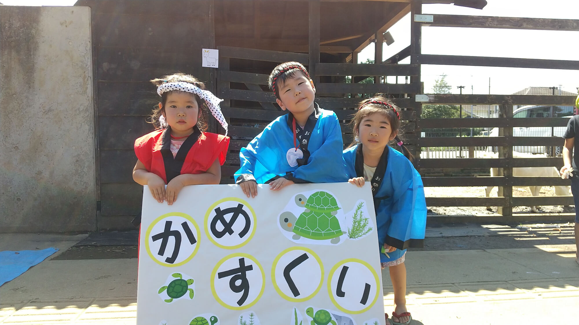 亀すくいの看板を持つ子どもたち