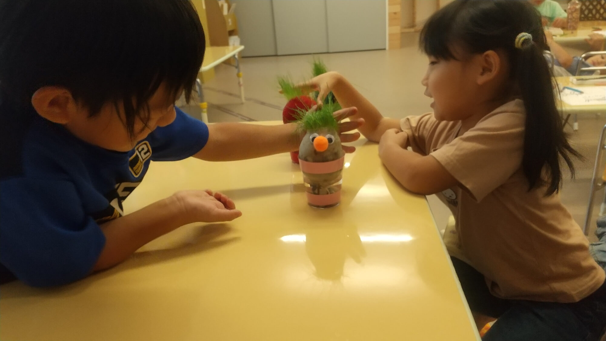 草が生えてきた「芝坊や」に興味を示す子どもたち