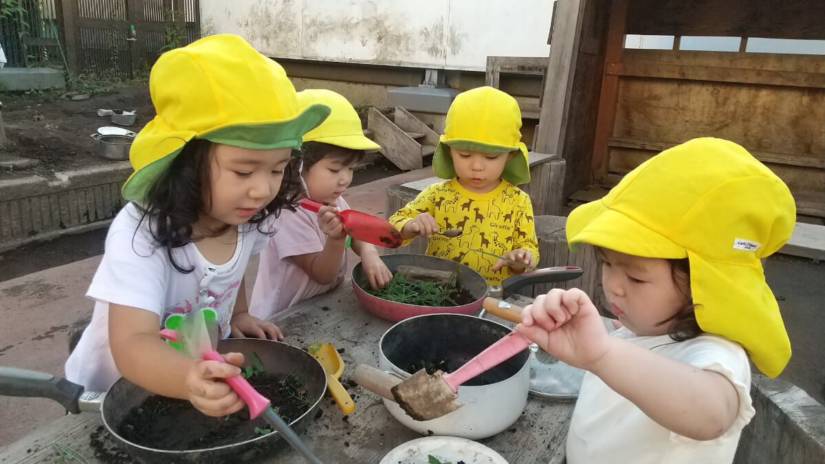 泥や雑草でクッキング遊びをする子どもたち