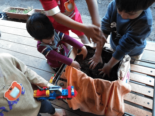 コンポストの土を混ぜる子どもたち