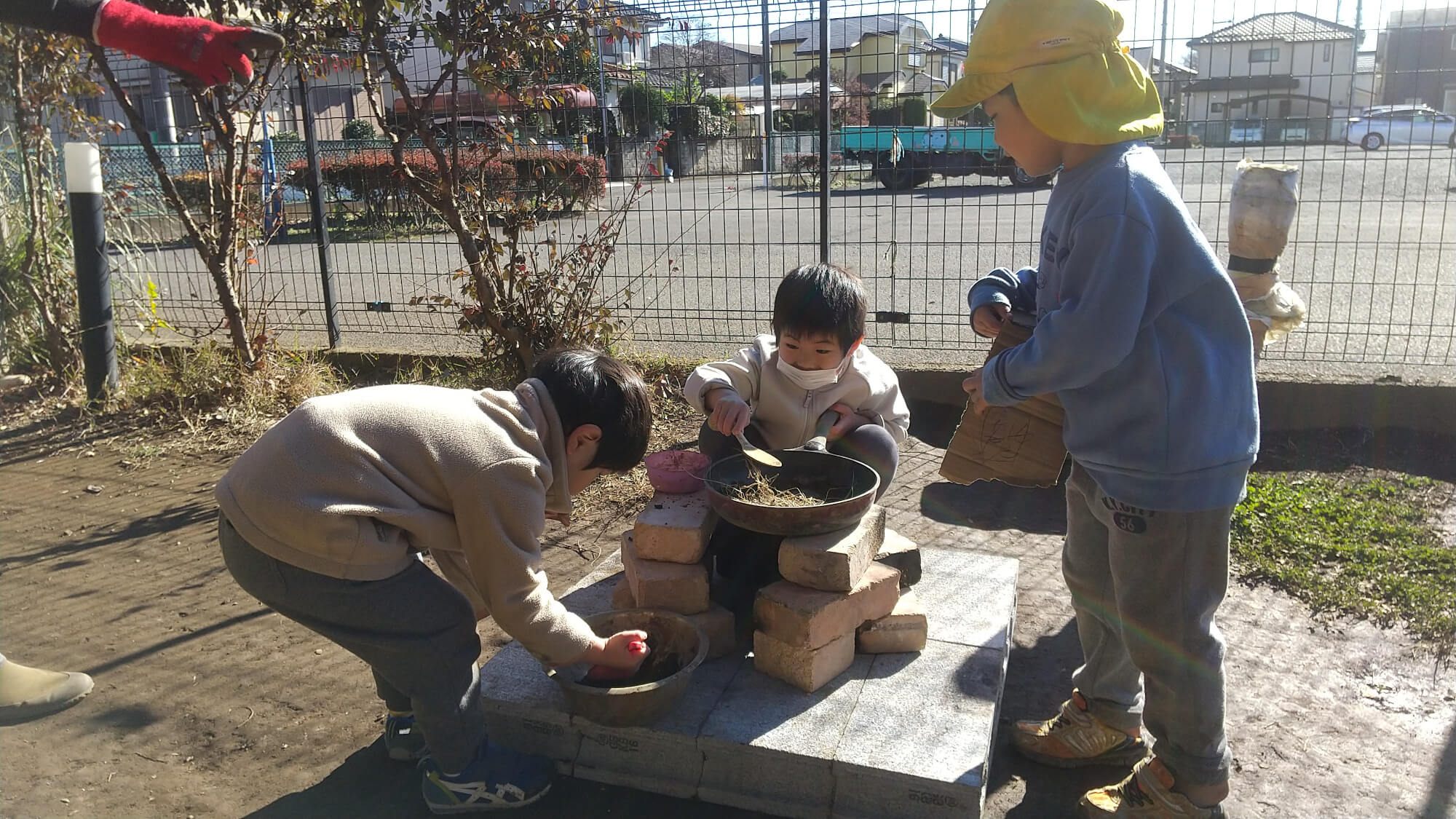 小さなかまどで遊ぶ子どもたち