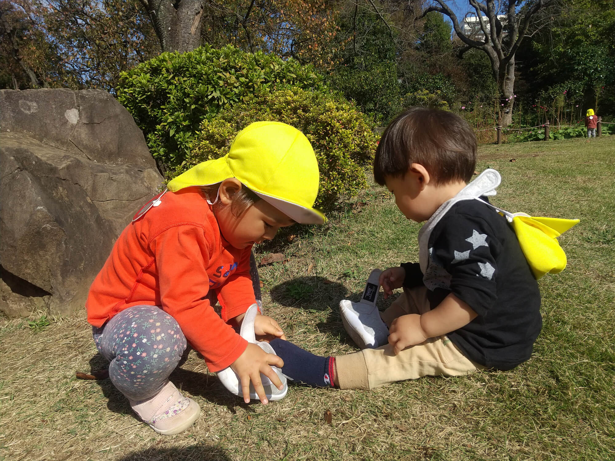 小さい子に靴を履かせてあげる子ども