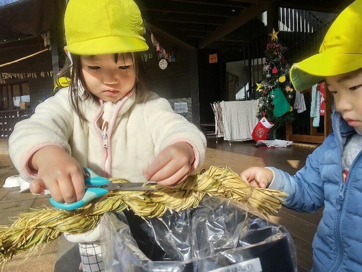 ハサミでしめ縄を整える子ども