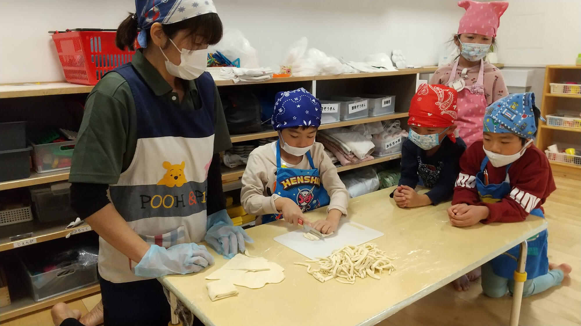 伸ばしたうどん生地を切る子ども