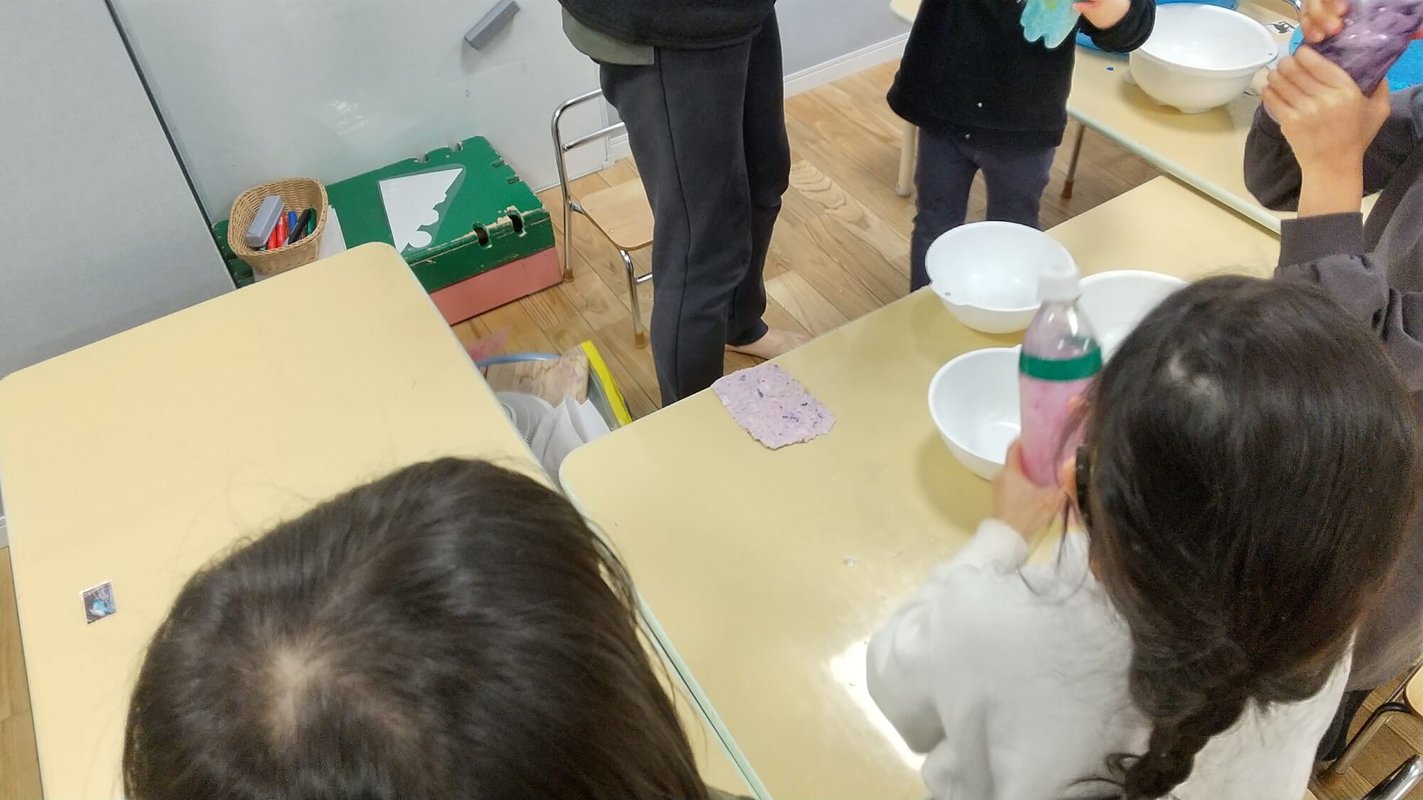 ペーパーと水を入れたペットボトルを振る子どもたち