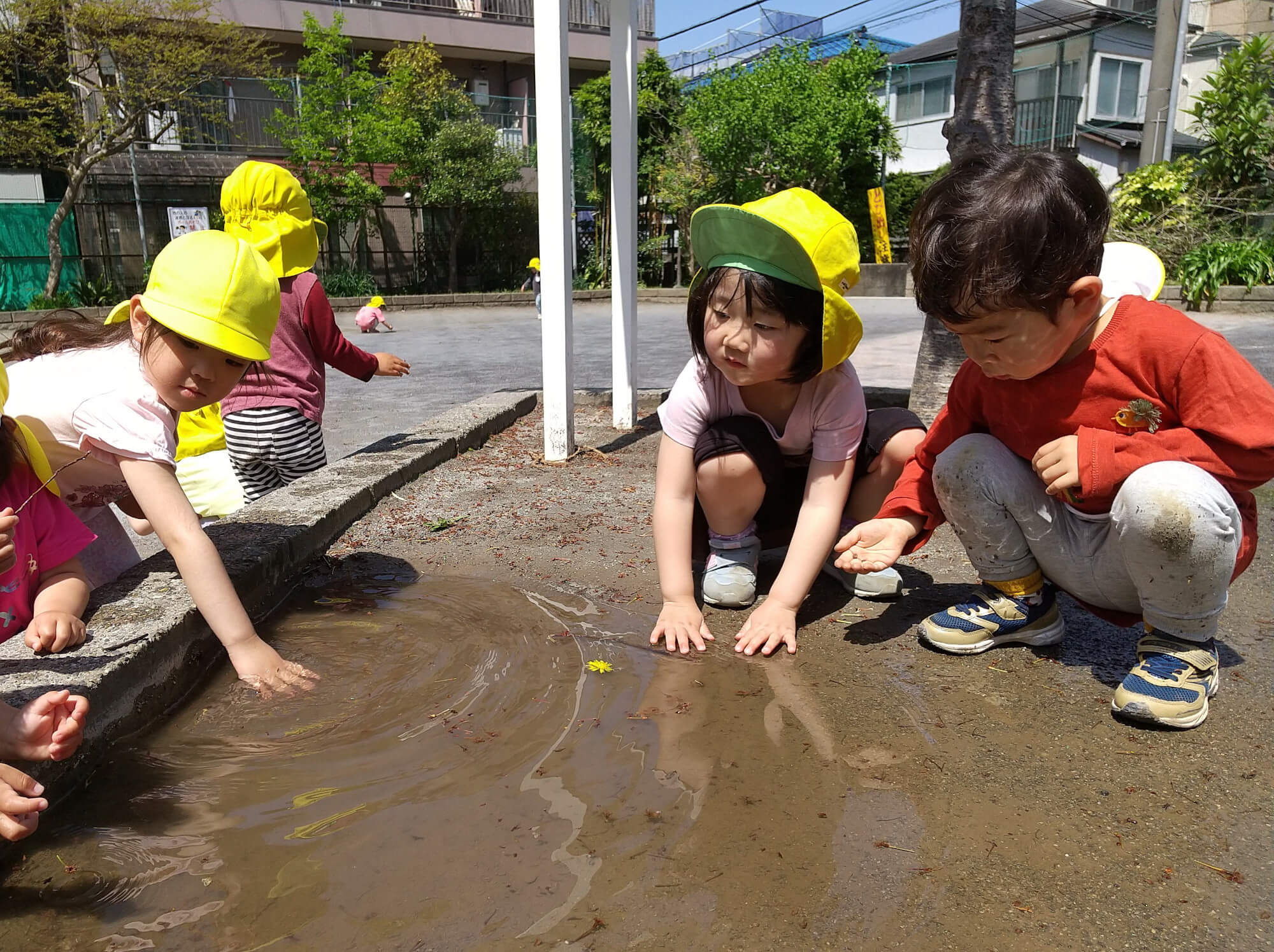 公園の水たまりで遊ぶ子どもたち