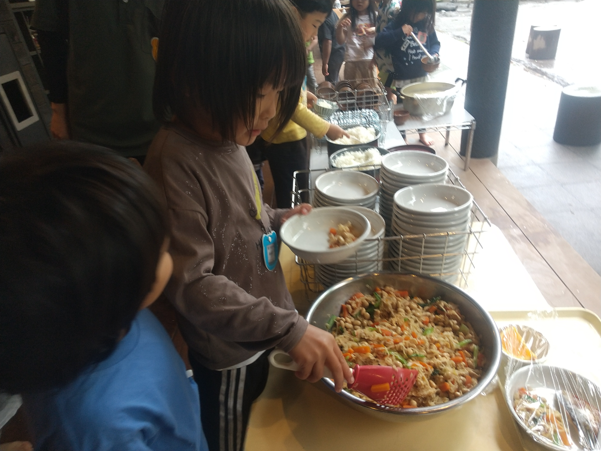 自分でおかずを盛り付ける子どもたち