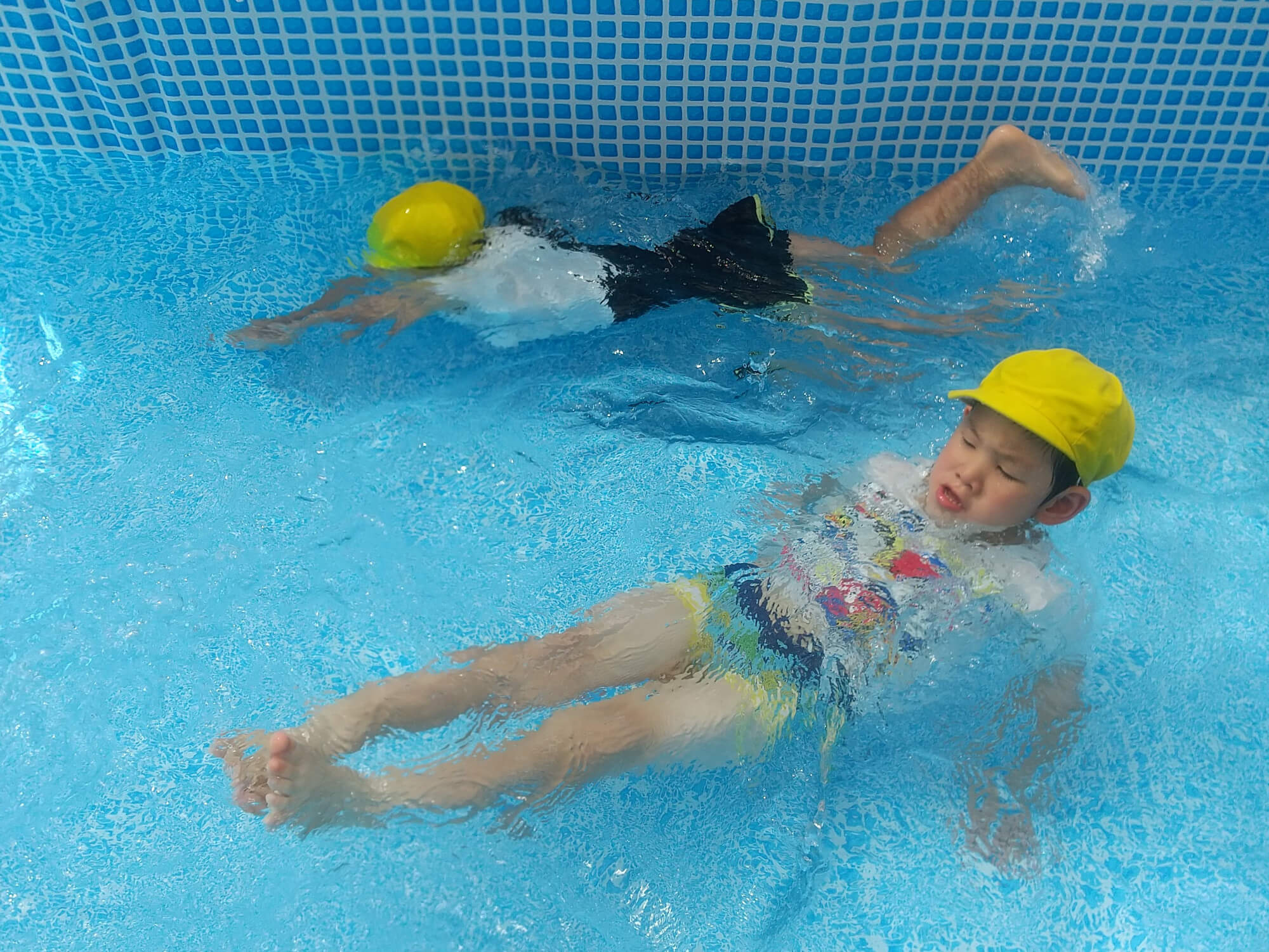 プールで水遊びをする幼児たち