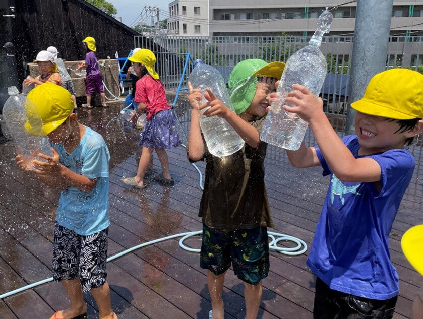 ペットボトルを使って水遊びをする子どもたち