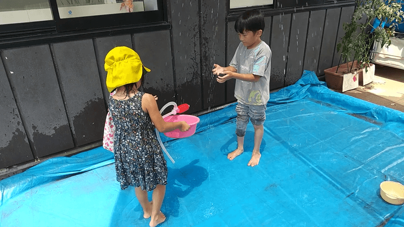 シャワーの水で遊ぶ子どもたち