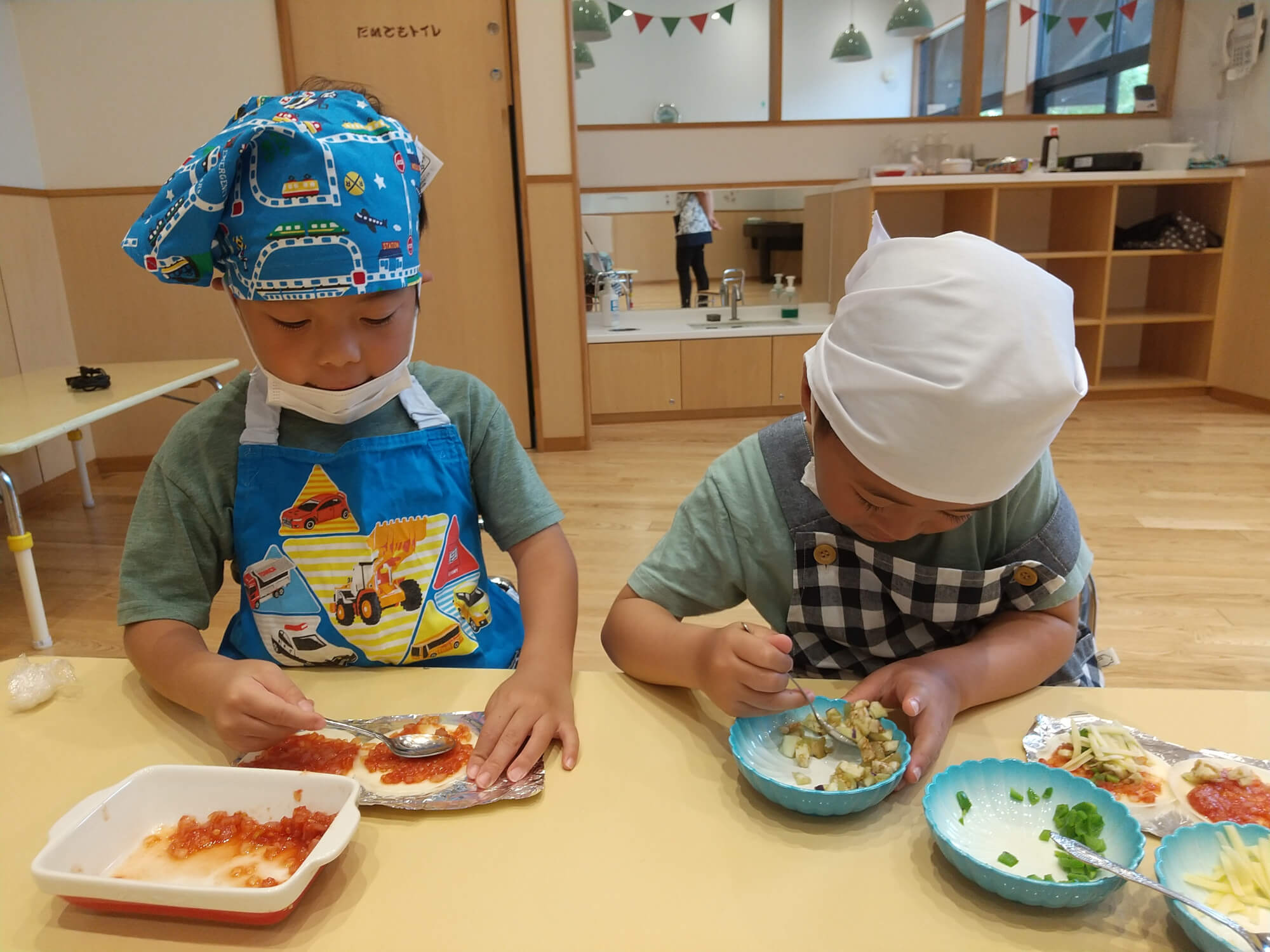 切った野菜でピザを作る子どもたち