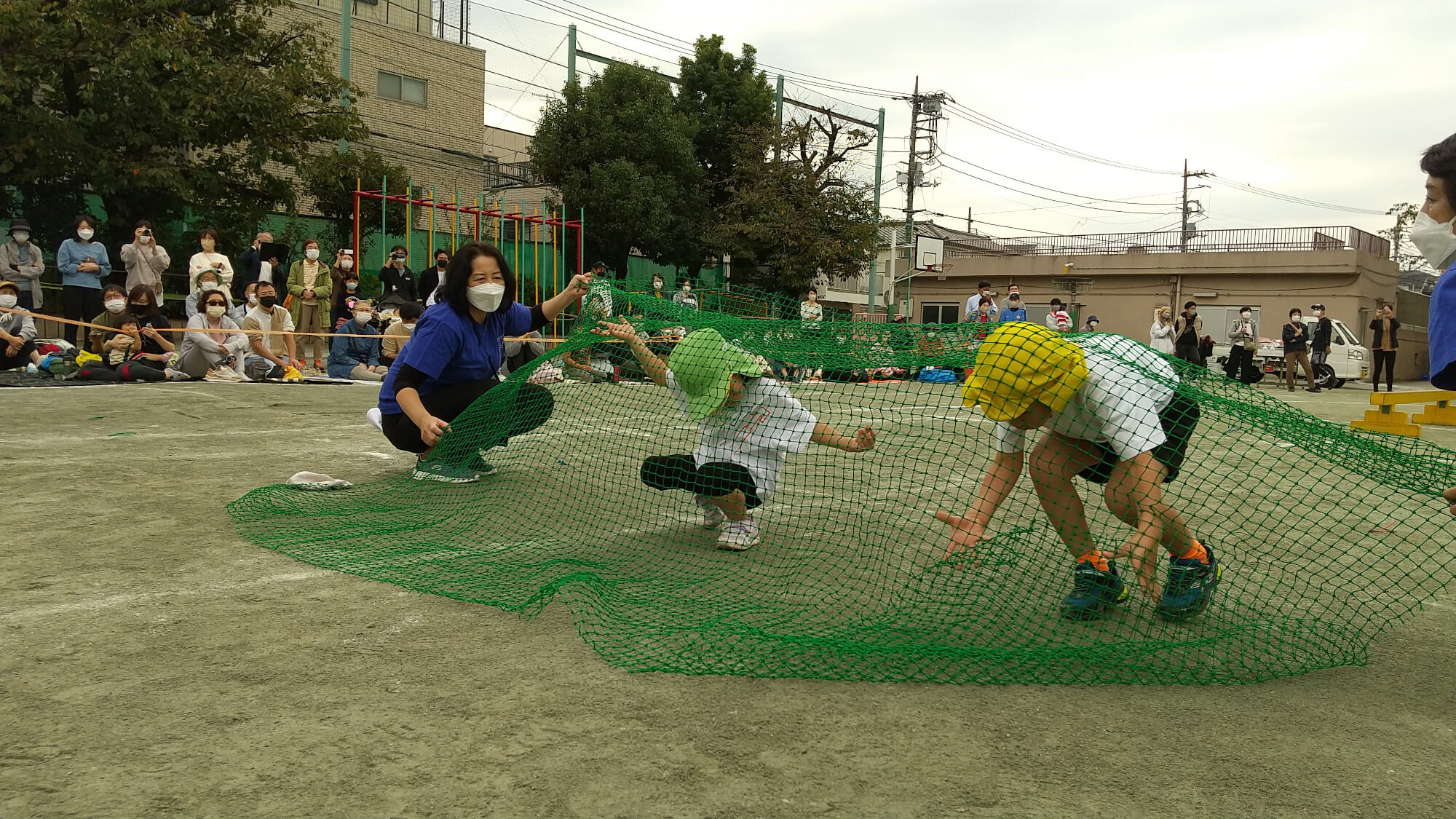 障害物競走でネットをくぐる子どもたち