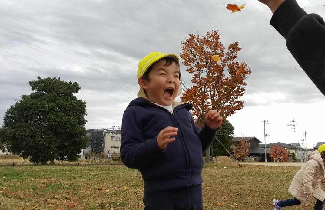 舞い上がる落ち葉を楽しむ子どもたち