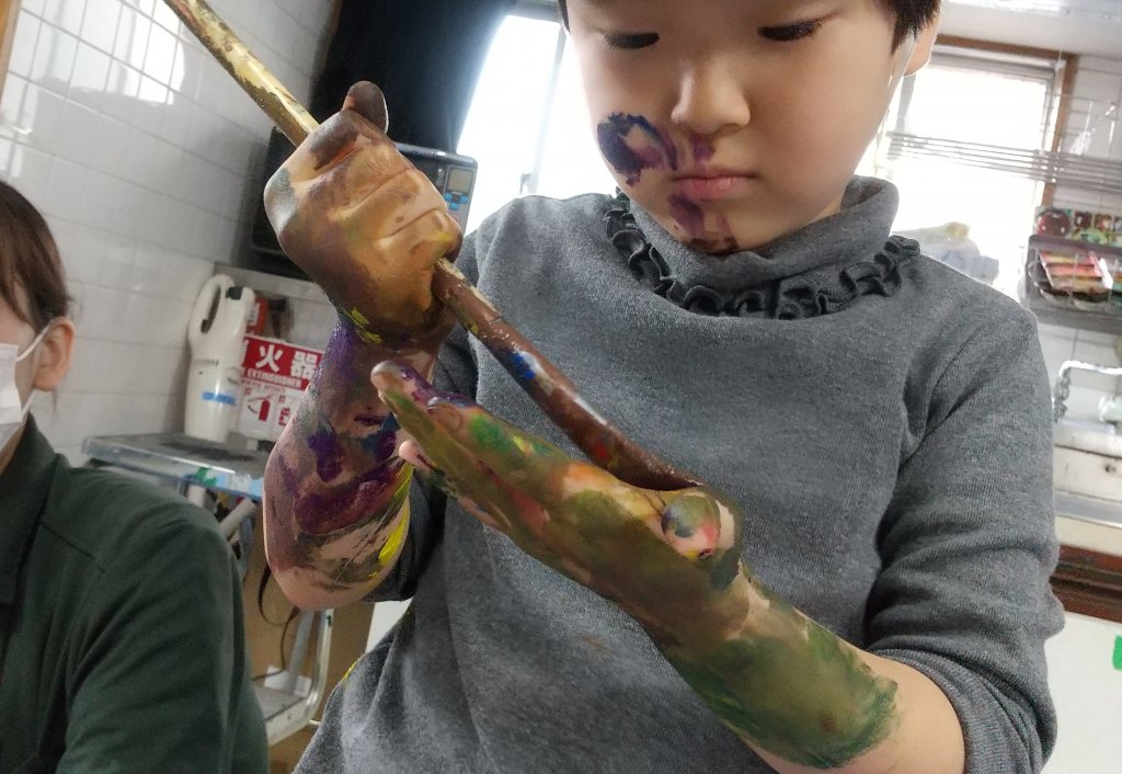 腕まで絵の具を塗っている子ども