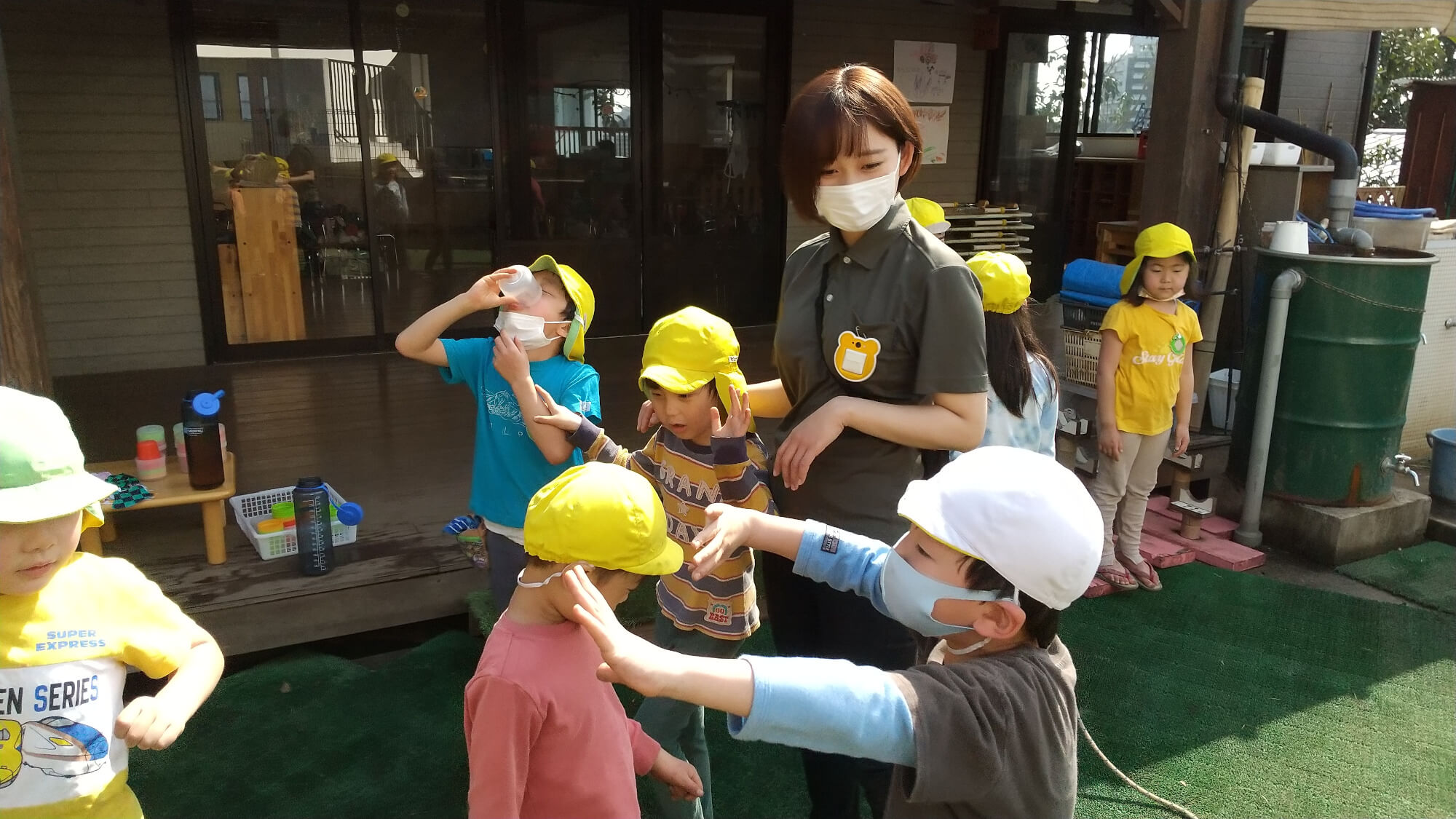 園庭で遊ぶ子どもたちを見守る職員