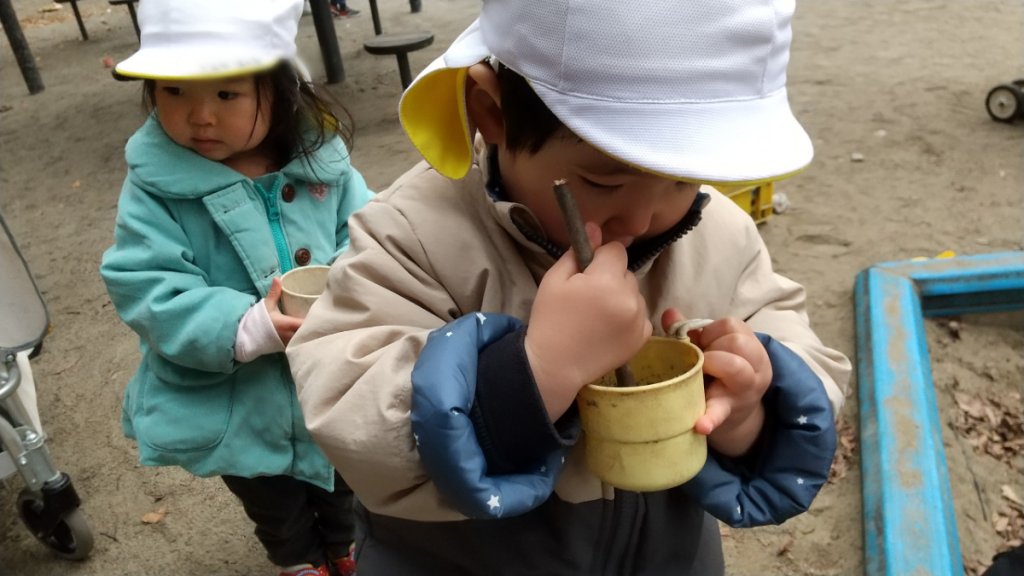 木の枝でかき混ぜる子どもたち