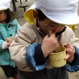 木の枝でかき混ぜる子どもたち