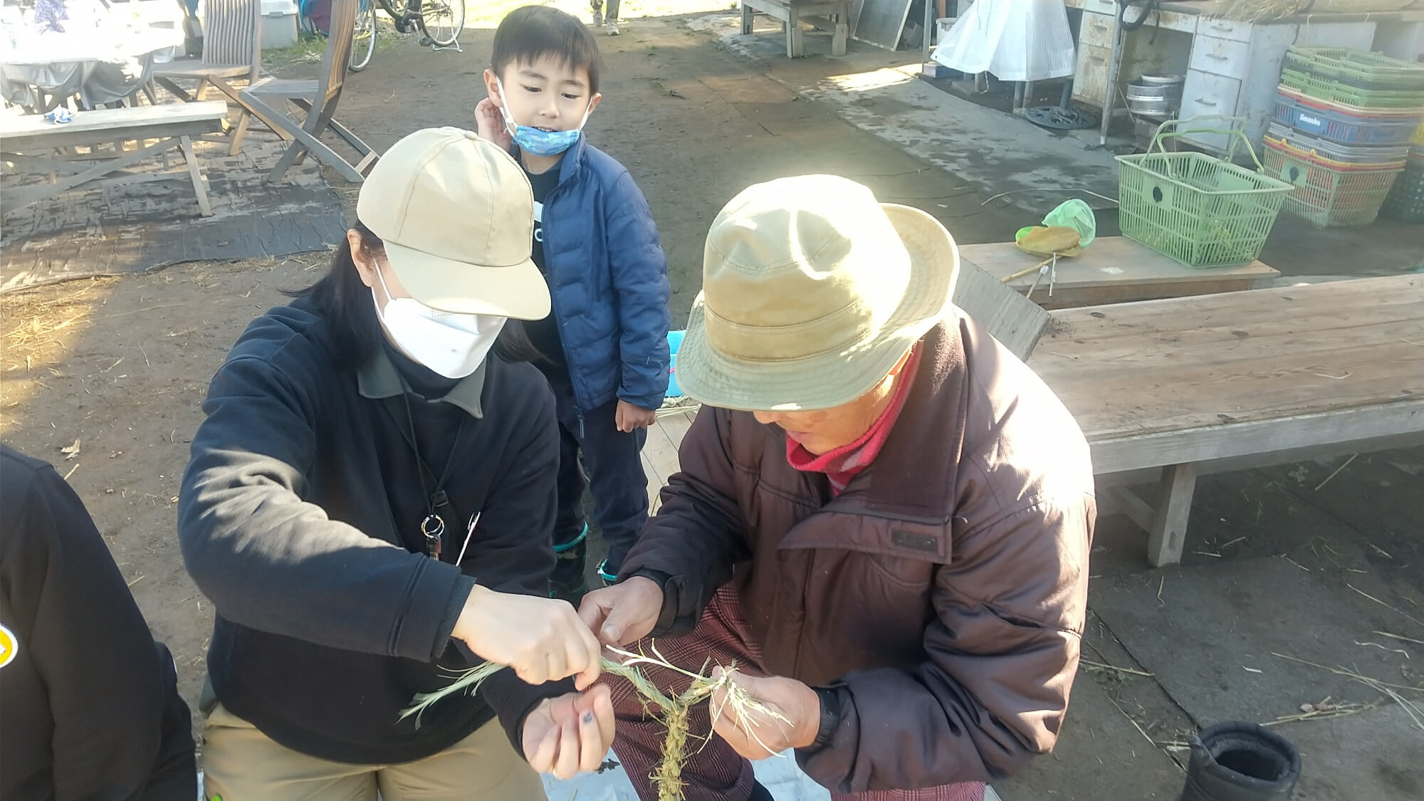 畑のおじさんにやり方を見せてもらう子ども