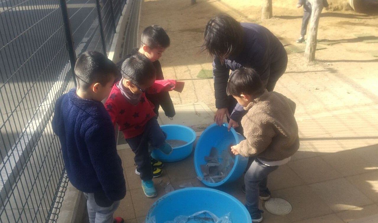 タライにできた氷で遊ぶ子どもたち