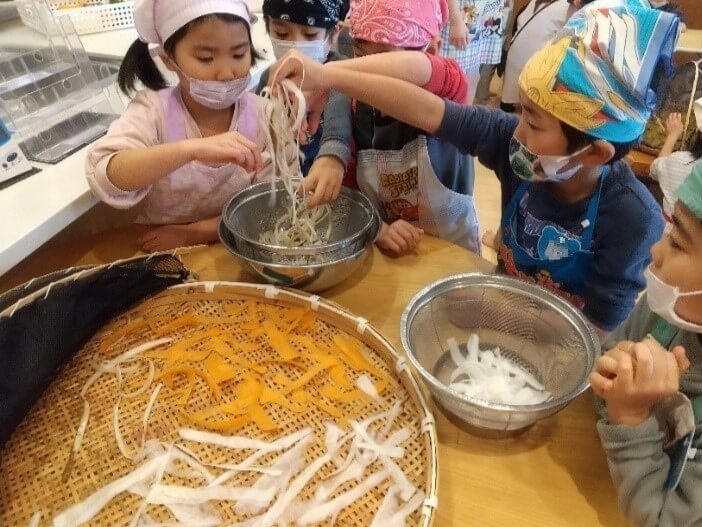 薄くスライスした野菜をザルに並べる子どもたち