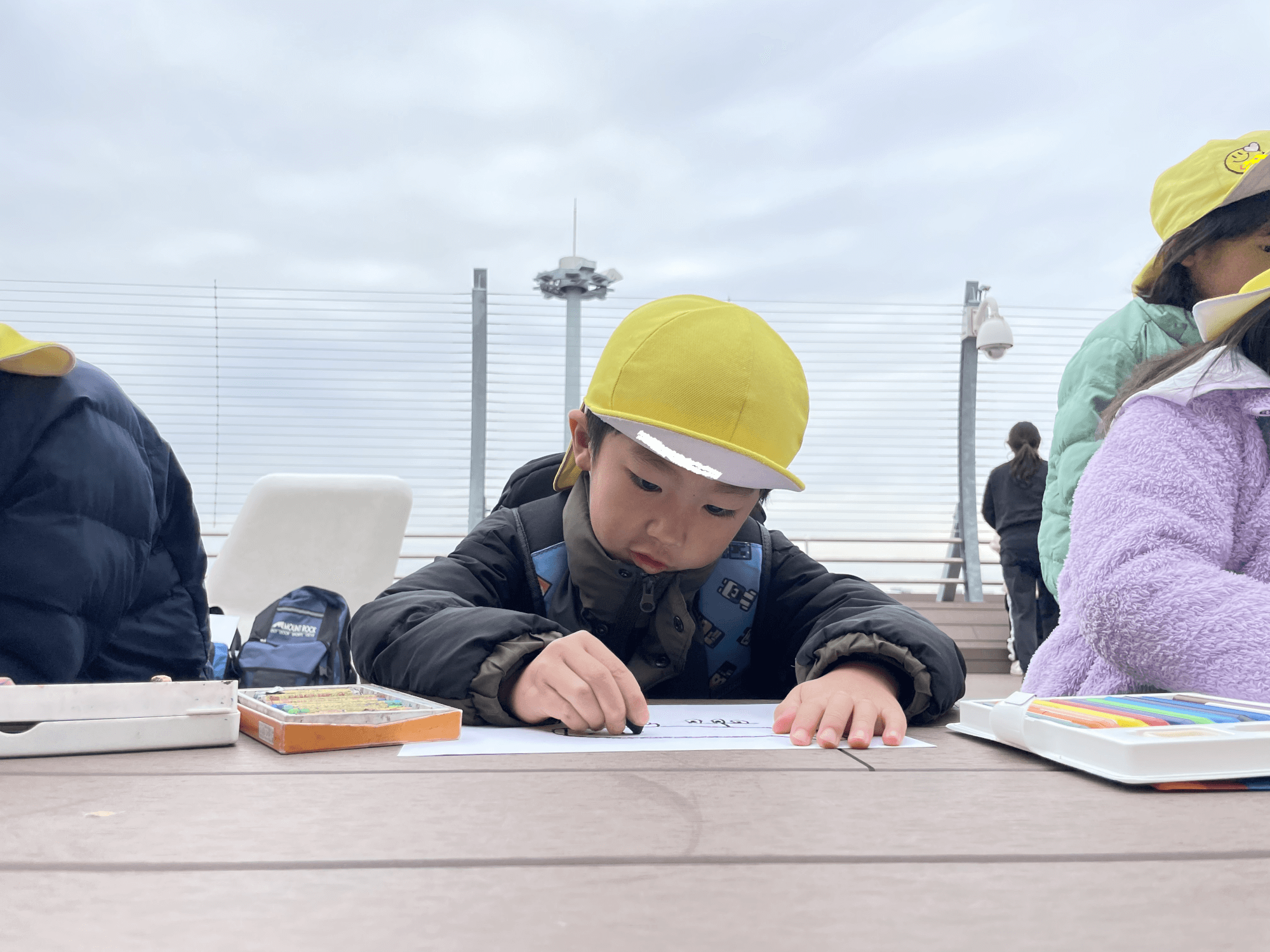 飛行機の離着陸を見ながら絵を描く子どもたち