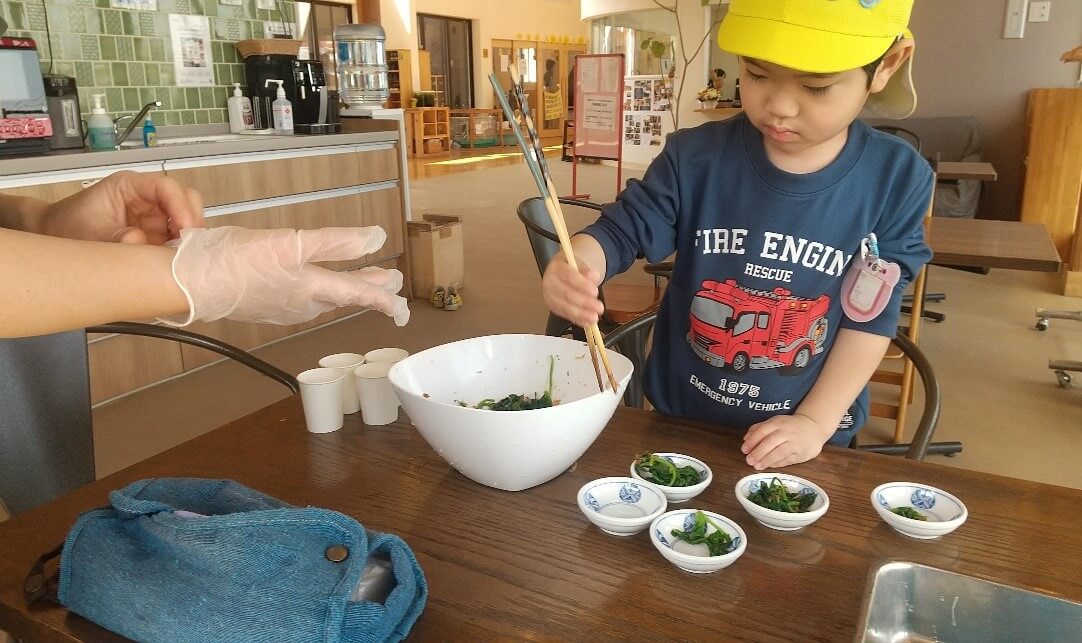 ほうれん草の味付けをする子ども