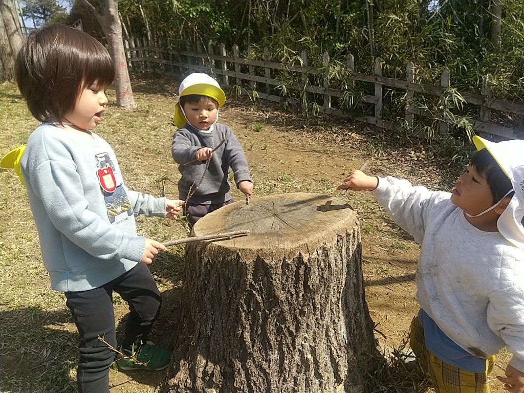 切り株をたたいて遊ぶ子どもたち