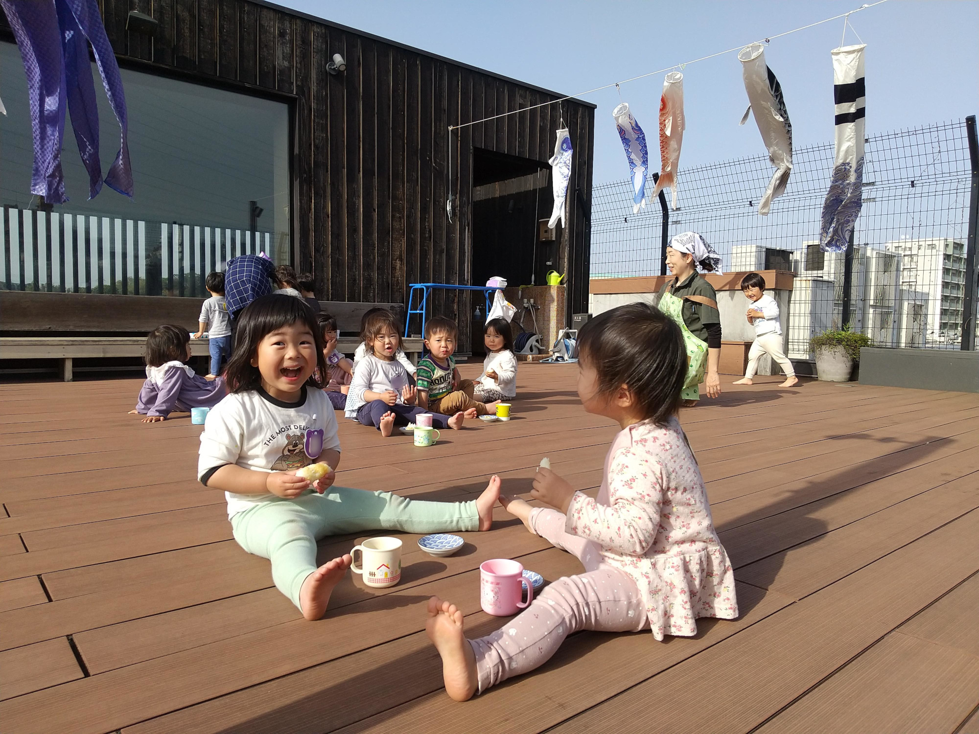 屋上で鯉のぼりを見ながらおやつを食べる子どもたち